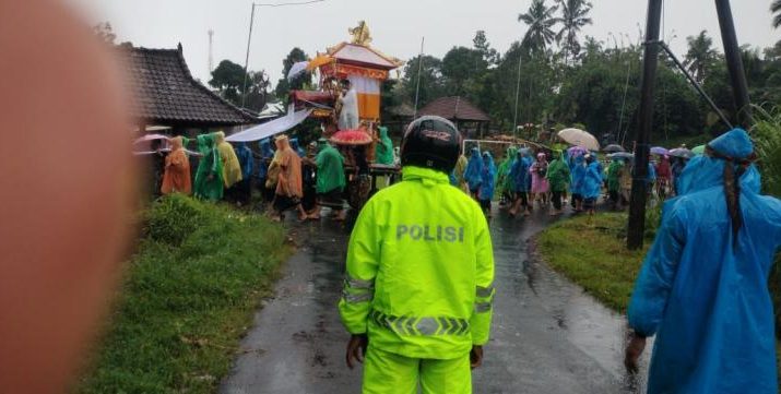 Di guyur hujan, Bhabinkamtibmas Desa Perean Kangin bersinergi dengan Pecalang Amankan pelaksanaan Upacara Pitra Yadnya / Ngaben